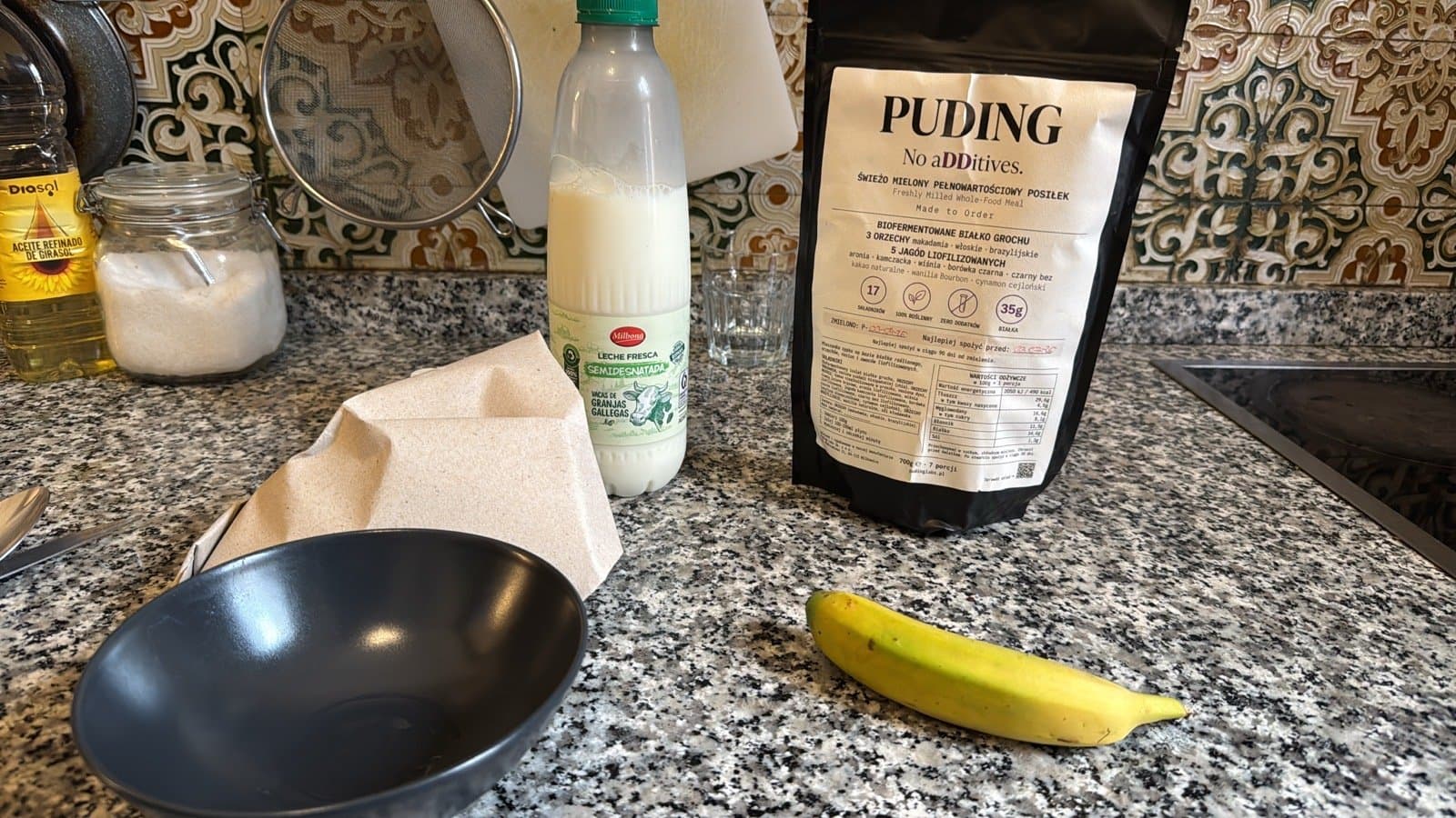 Blat w kuchni hostelu: mleko, paczka PUDING, banan i pusta miska