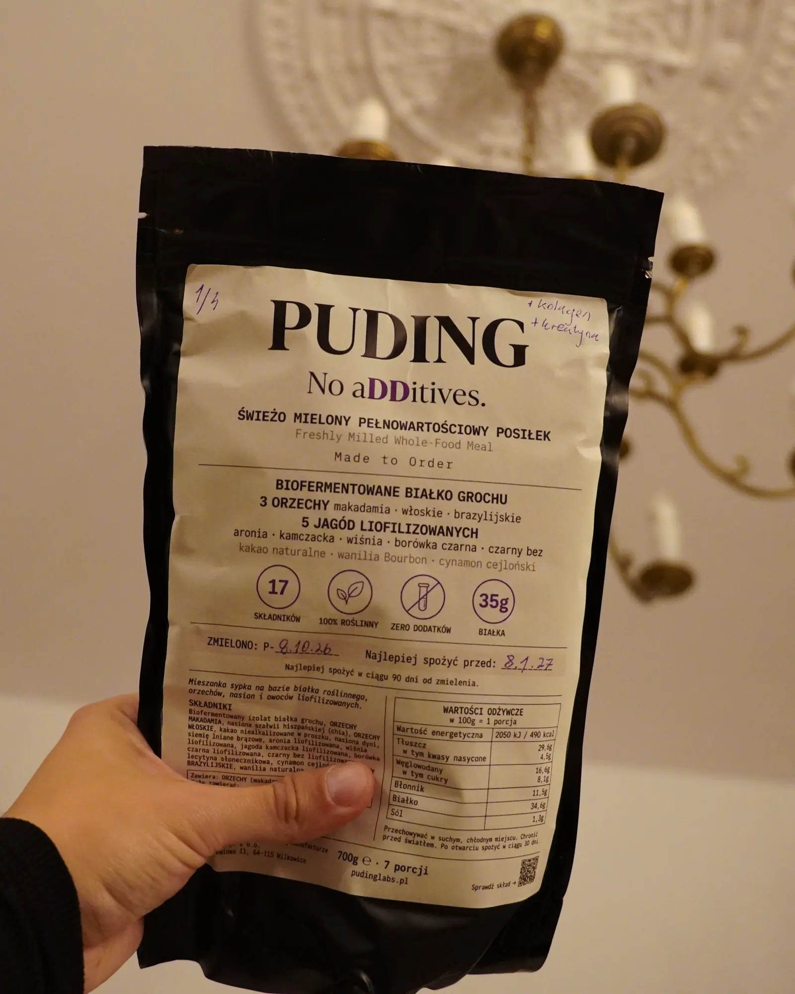 Paczka PUDING trzymana w dłoni, na etykiecie data mielenia i dopisek flamastrem